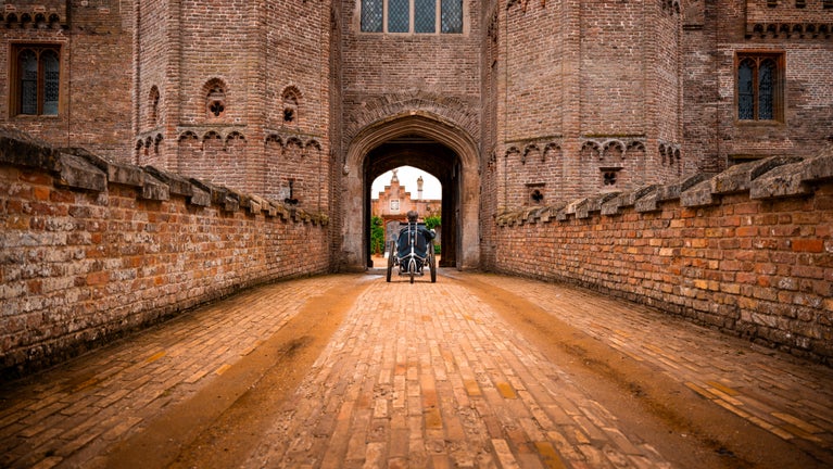 A young visitor in a powered wheelchair accessing the courtyard via the Gatehouse at Oxburgh Estate